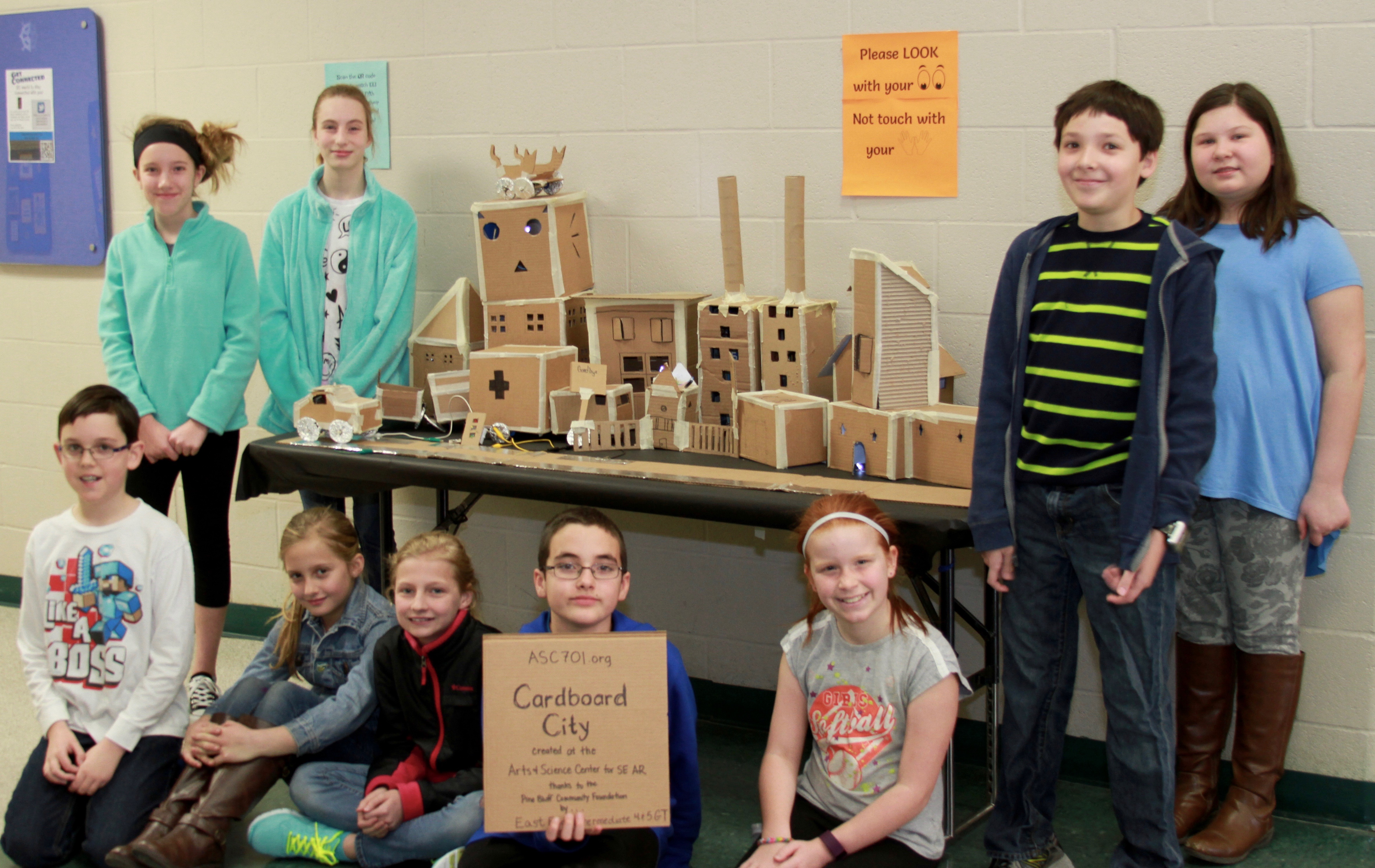 Students pose next to cardboard city